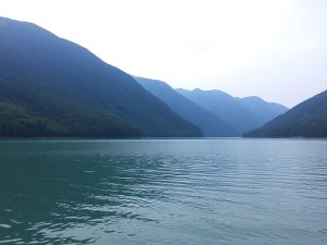 Peisaj montan liniștit cu păduri și un lac răcoros.